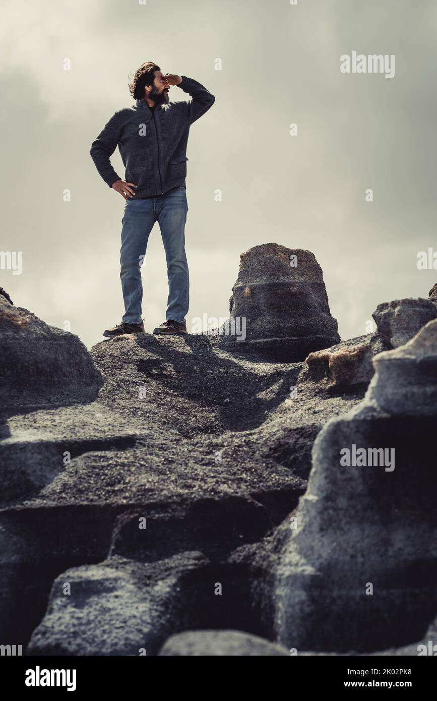 Man standing and looking for on a gray stones scenic place. Concept of travel and adventure tourism. Man and freedom in alternative holiday journey vacation in vertical image Stock Photo