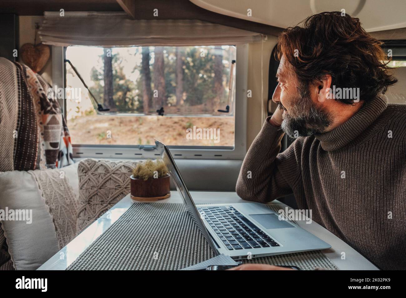 Off grid job lifestyle with mature man working on laptop inside a