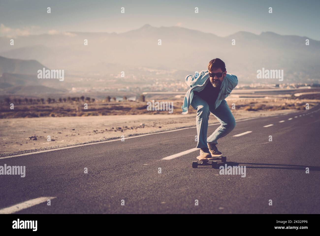 Adult youth man go speed on longboard skate on asphalt road. Mature people enjoy outdoor leisure activity. Freedom and youthful lifestyle concept. Enjoying life and scenic place Stock Photo