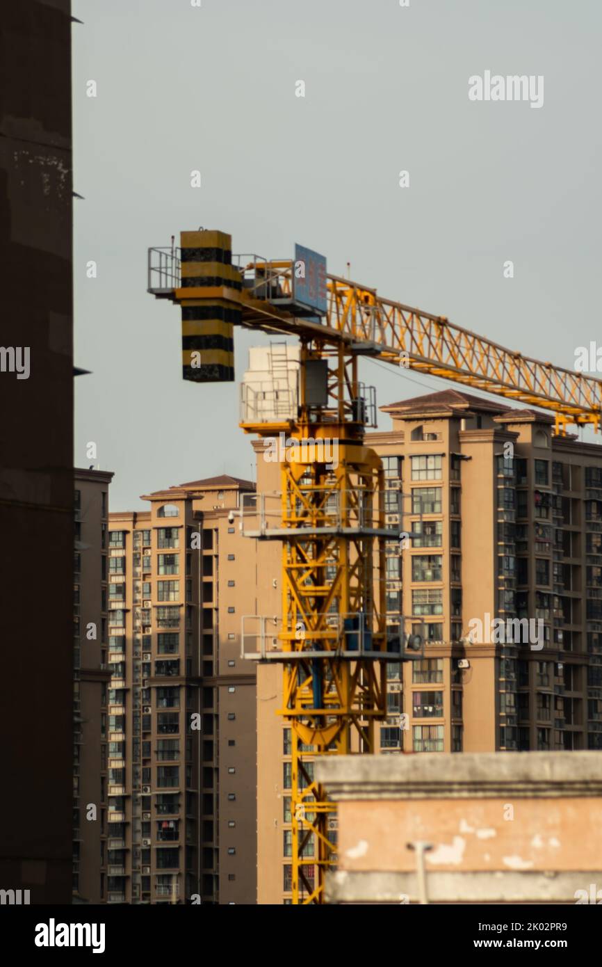 A vertical shot of a construction crane between buildings Stock Photo ...