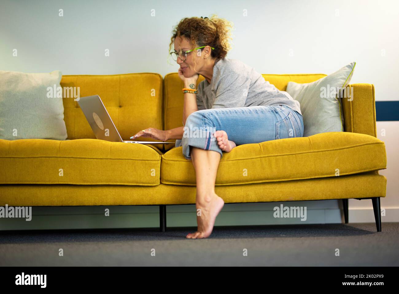 Smart working modern female people using laptop computer at home comfortably sitting on the sofa