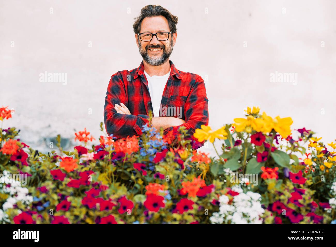 Portrait of happy man florist smiling and posing with lot of blossom colorful flowers in front of him. White background. Concept of store business floreal nature. Spring concept business lifestyle male people Stock Photo