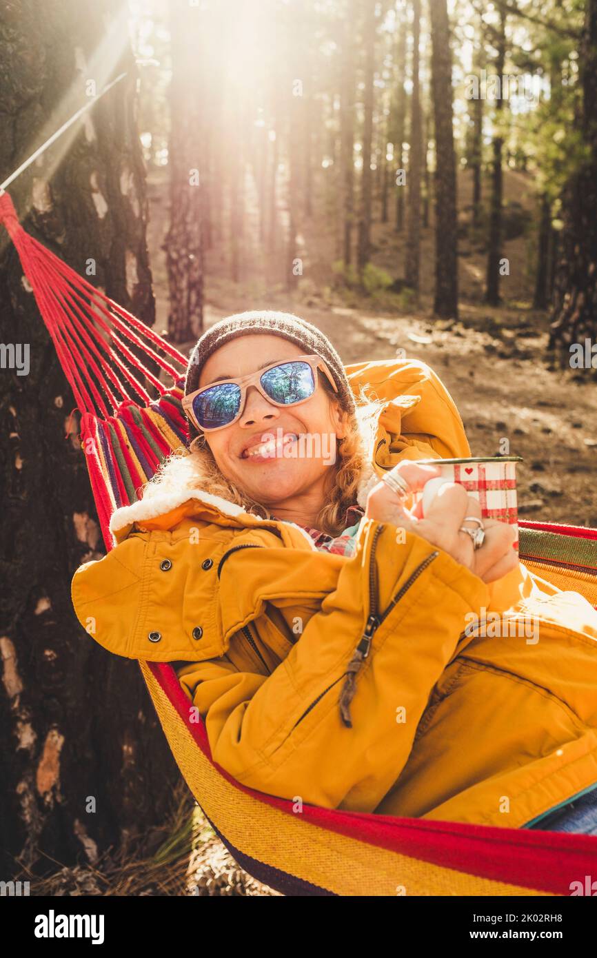 Happy young adult woman portrait smile and enjoy the nature woods forest leisure activity - cheerful female people natural lifestyle at the park - high trees and sunlight in background Stock Photo