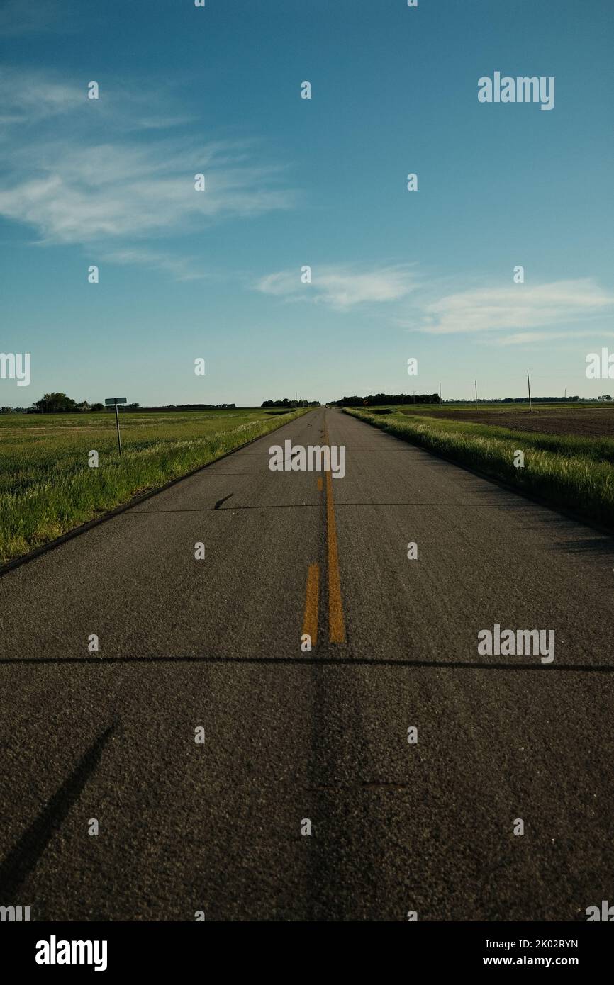 A vertical shot of an asphalt road through fields Stock Photo - Alamy