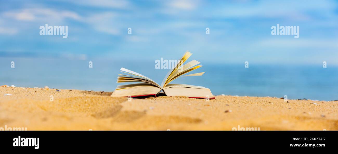 Book on beach with blue sea in background Stock Photo