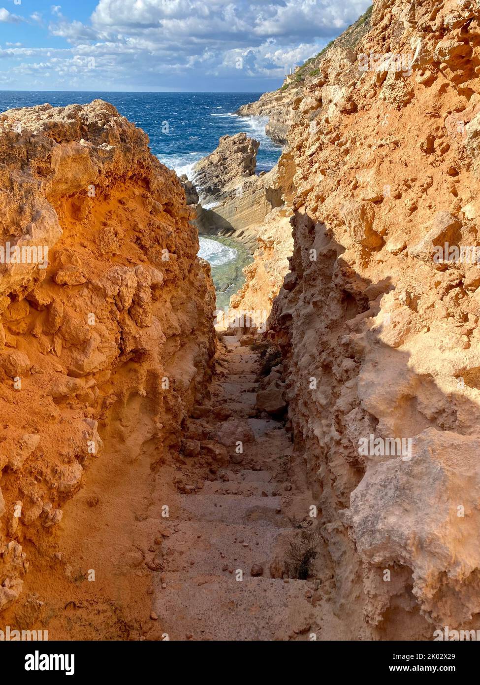 A vertical shot of the narrow footpath surrounded by brown rocks ...