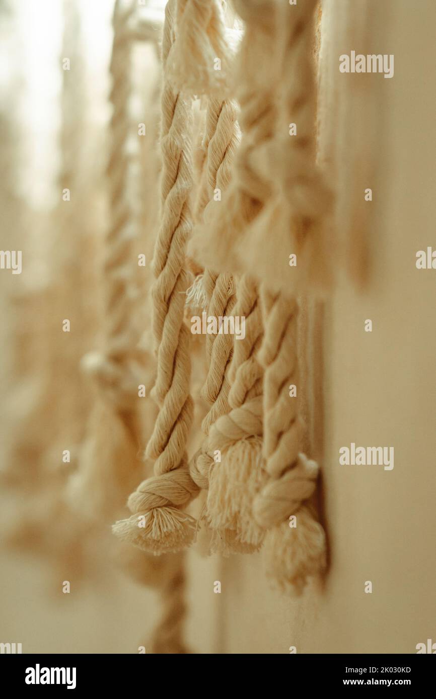 A vertical shot of threaded ropes against a wall with a blurry ...