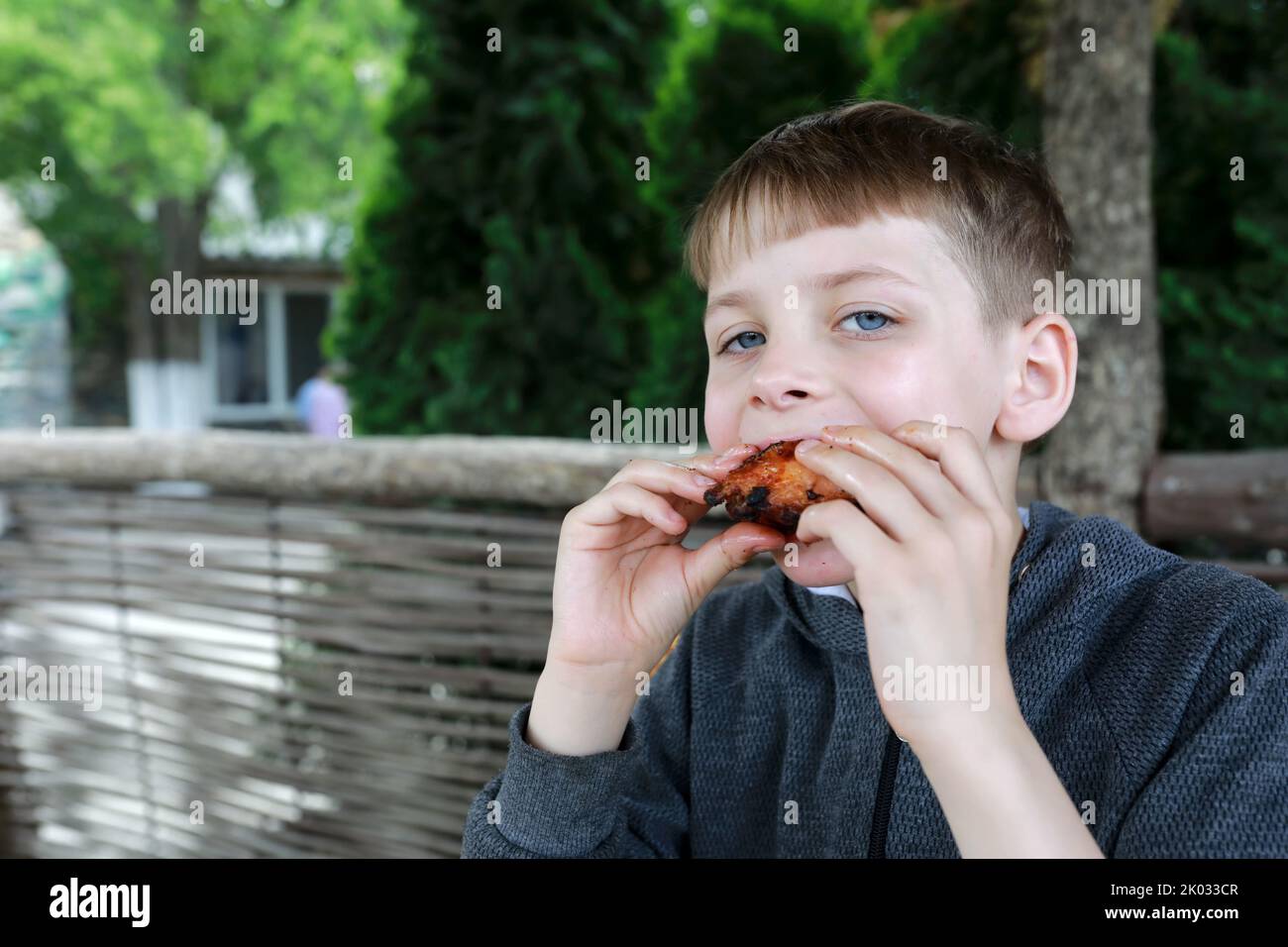 Kid has grilled chicken wings on restaurant terrace Stock Photo Alamy