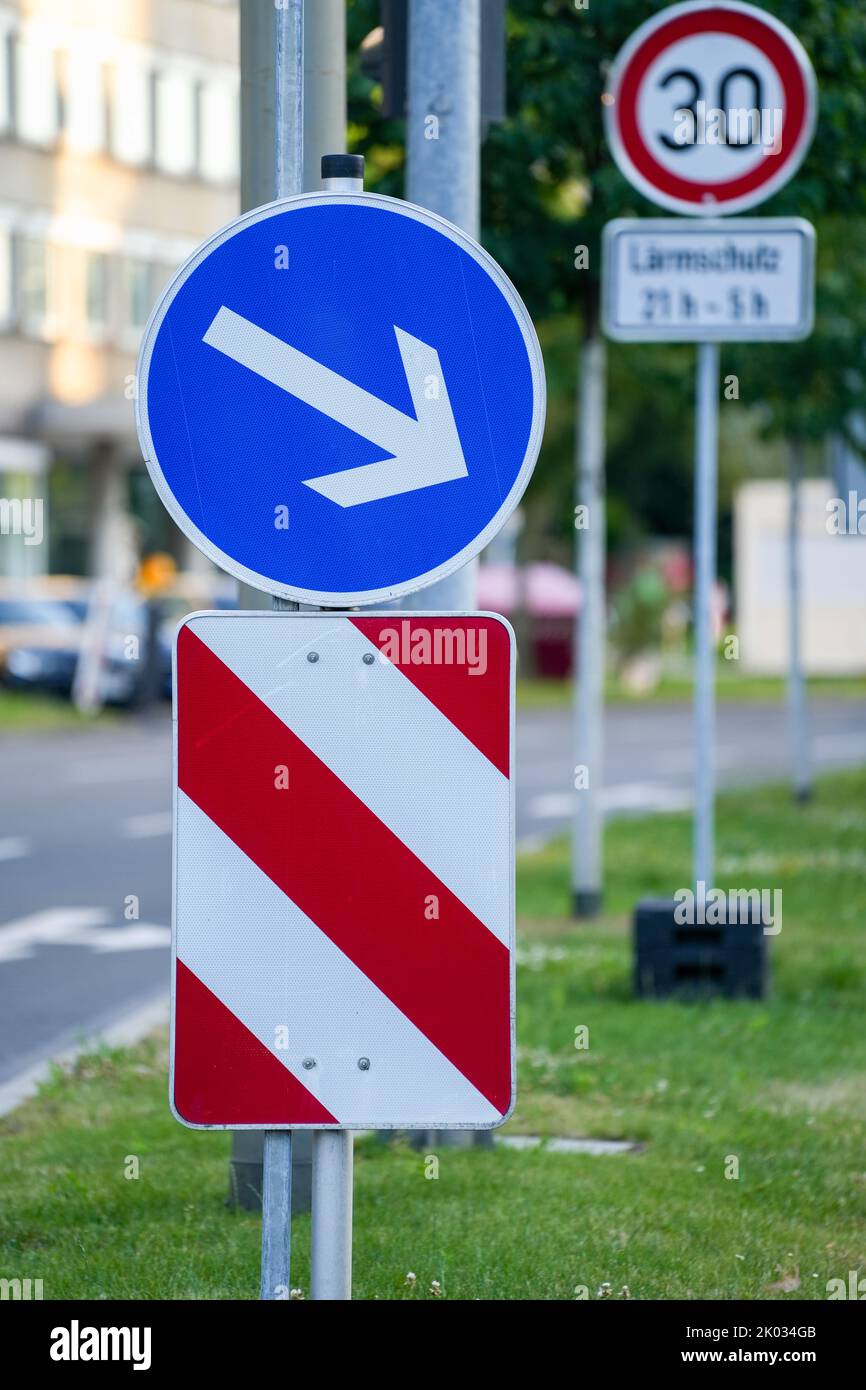 A vertical closeup shot of a blue circular traffic sign with an arrow