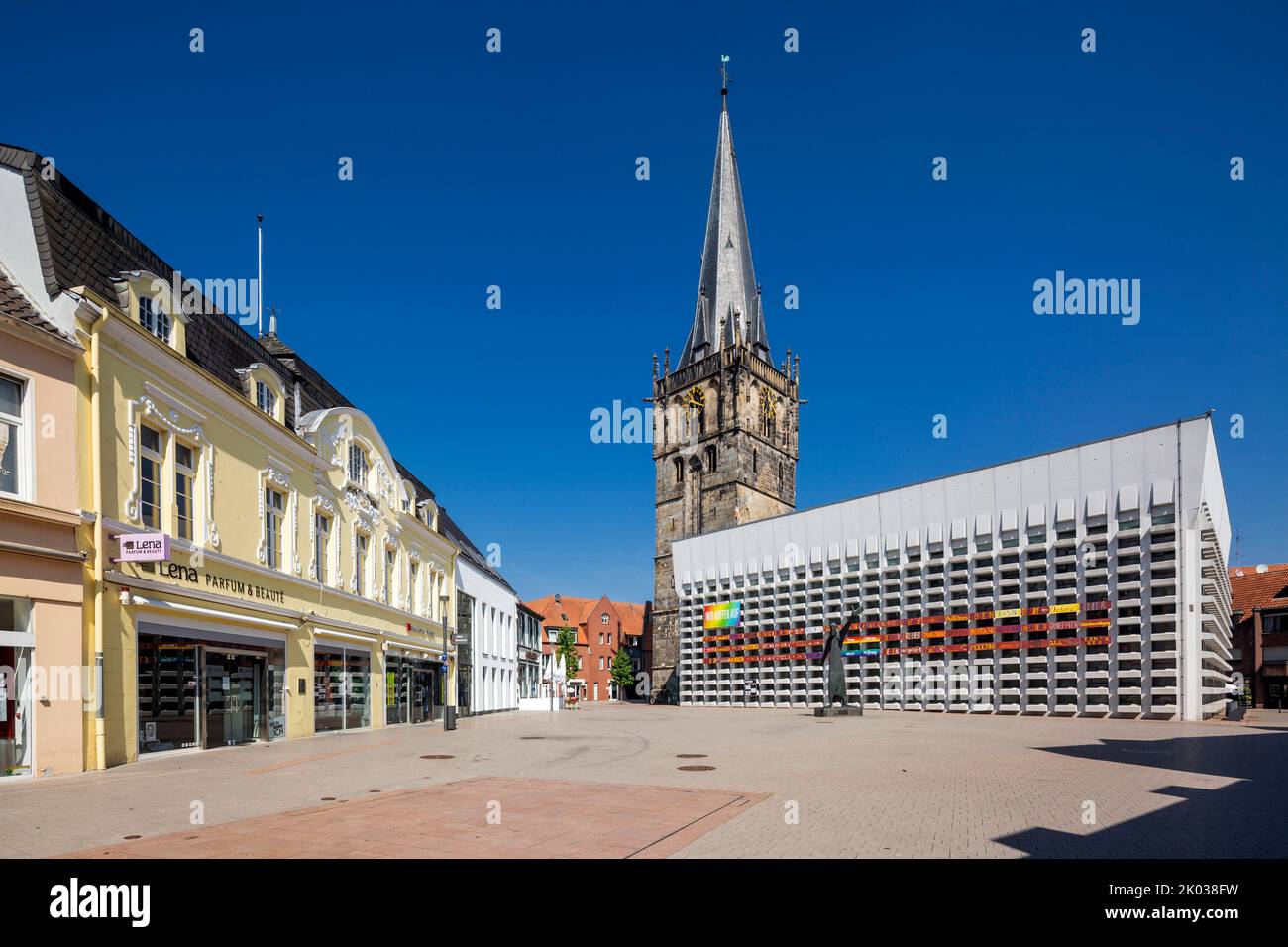 Germany, Ahaus, Westmuensterland, Muensterland, Westphalia, North Rhine-Westphalia, Catholic Church St. Mariae Himmelfahrt at the market, the steeple comes from the old church and the nave was added as a concrete building by Erwin Schiffer, in front of it the sculpture 'The Admonisher' by Hilde Schuerk Frisch, on the left the residence and business house of the Beckering family Stock Photo
