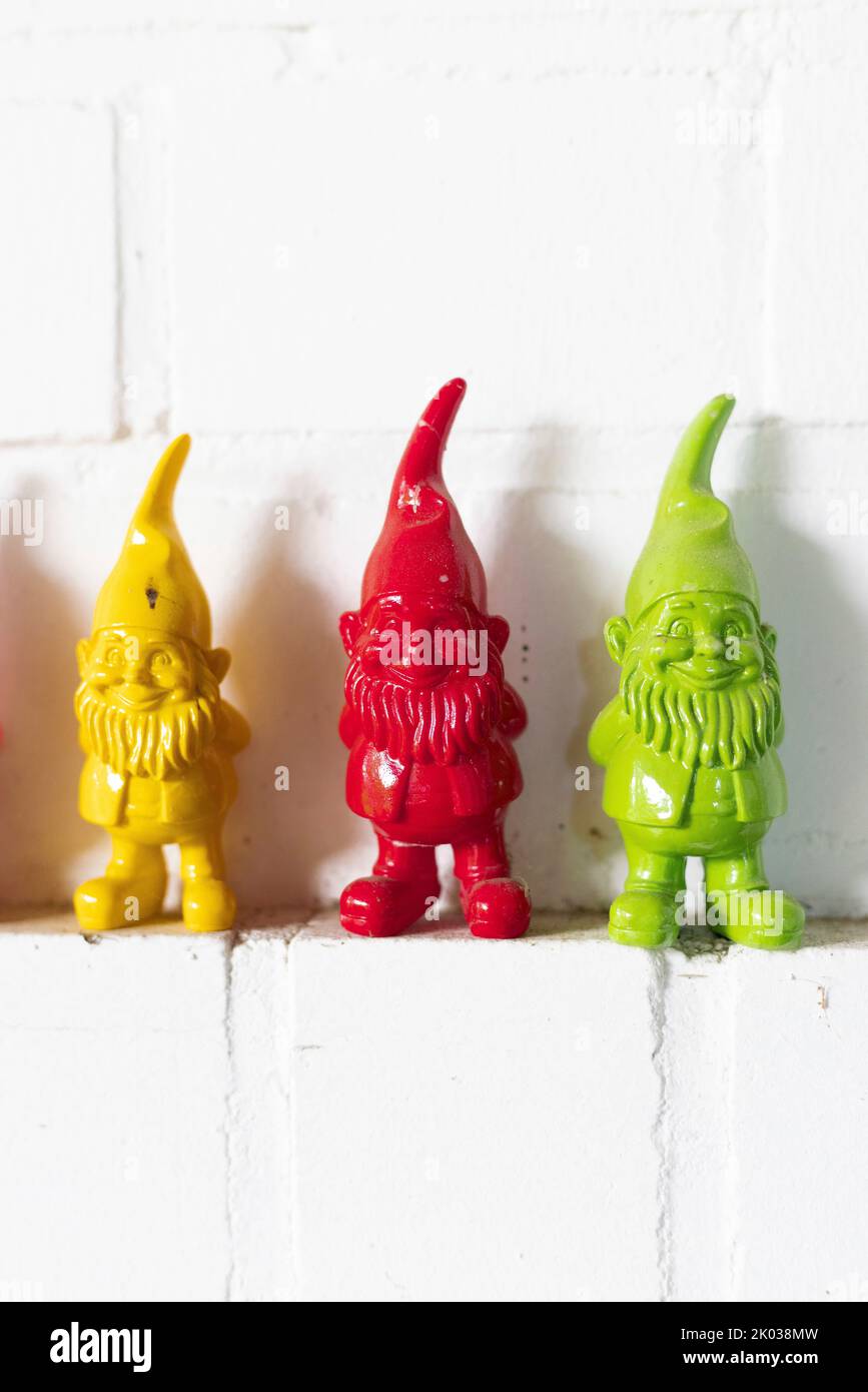 Three colorful dwarfs on a wall ledge Stock Photo