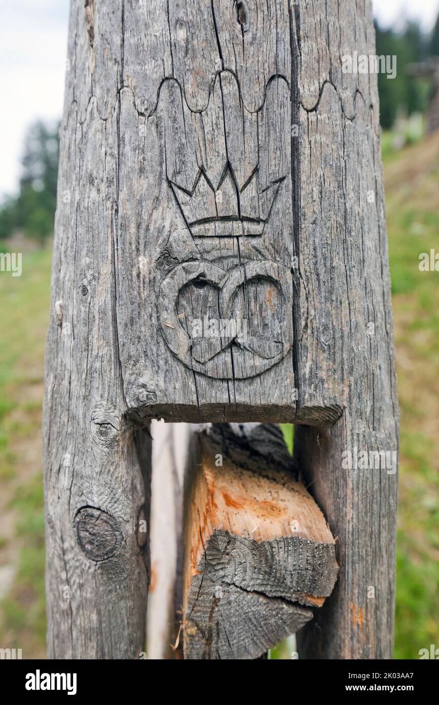 Pretzel and crown as baker's symbol on wooden pole in South Tyrol's Ulten Valley Stock Photo