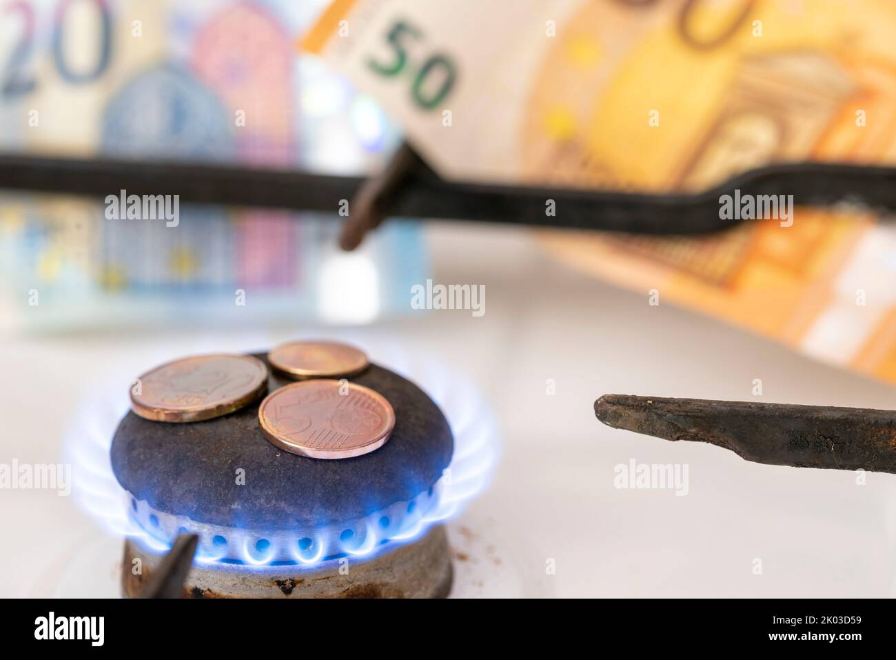 Gas stove hob, gas flame, small change, banknotes behind it Stock Photo