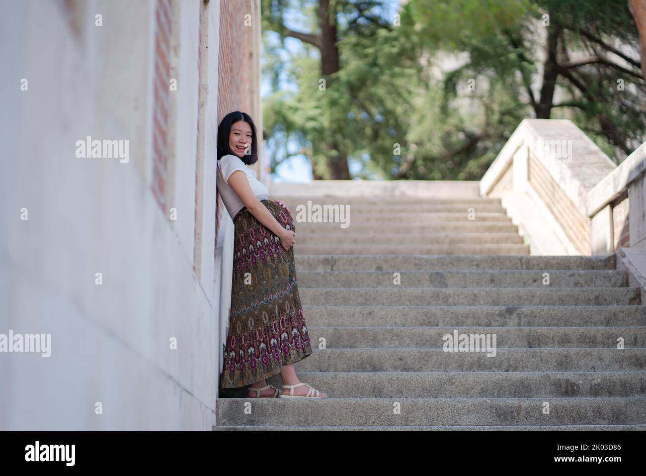 young happy and beautiful Asian Japanese woman posing outdoors happy and cheerful pregnant showing her belly proud smiling in pregnancy and maternity Stock Photo