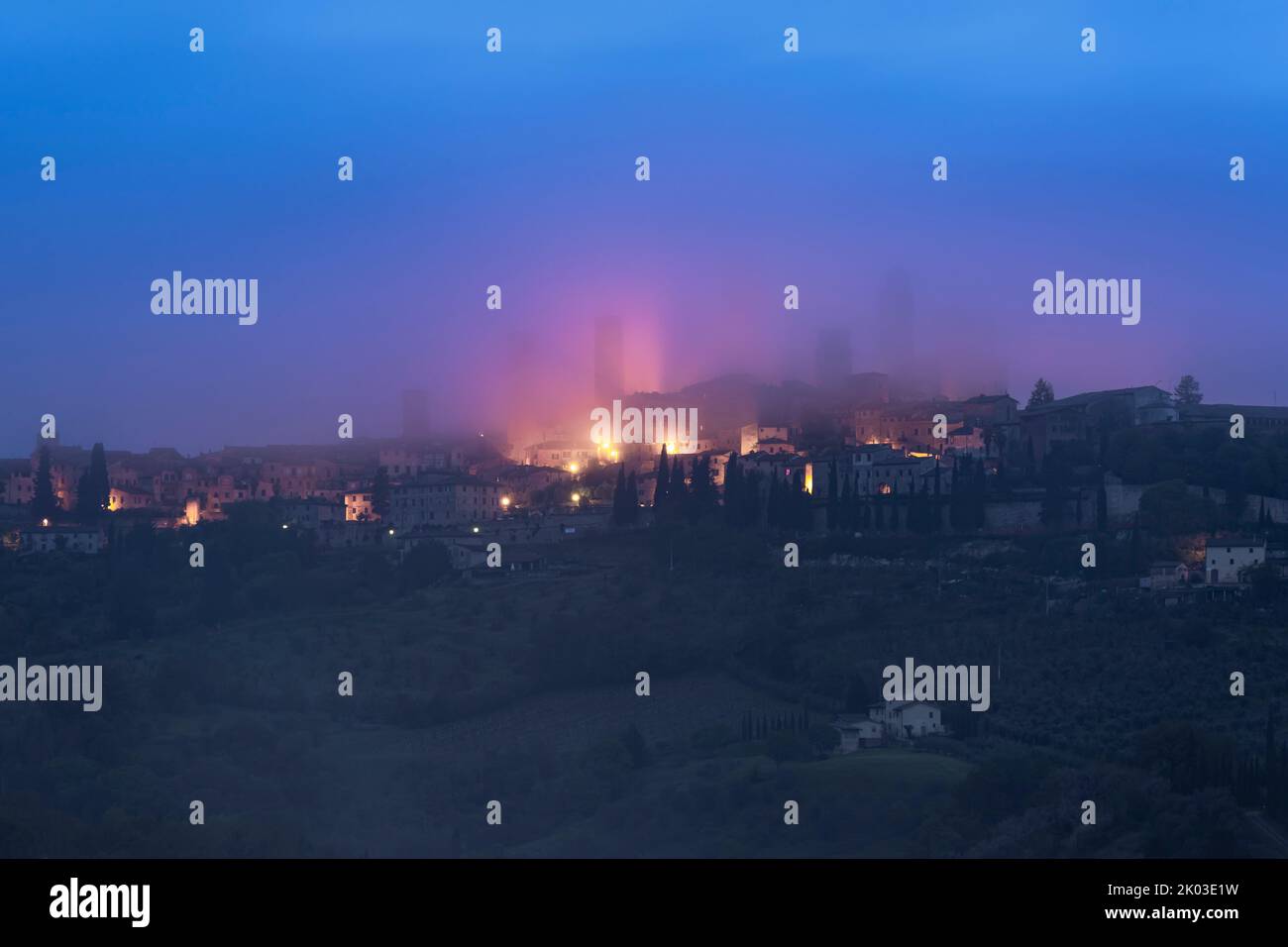 Blue hour, San Gimignano wrapped in fog, Siena, Tuscany, Italy Stock Photo