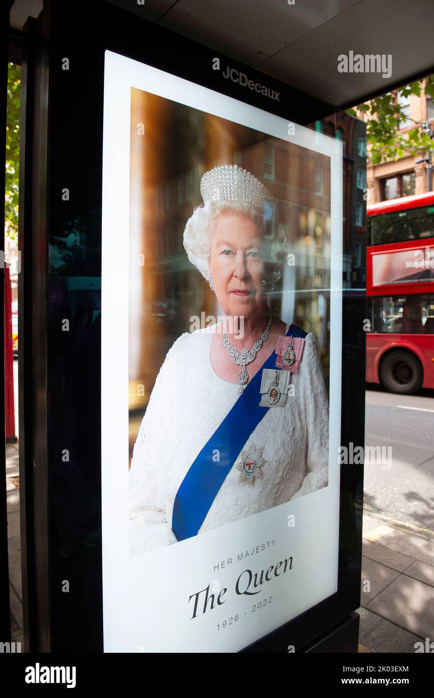 A bus stop digital advertising sign displays a portrait of Queen ...