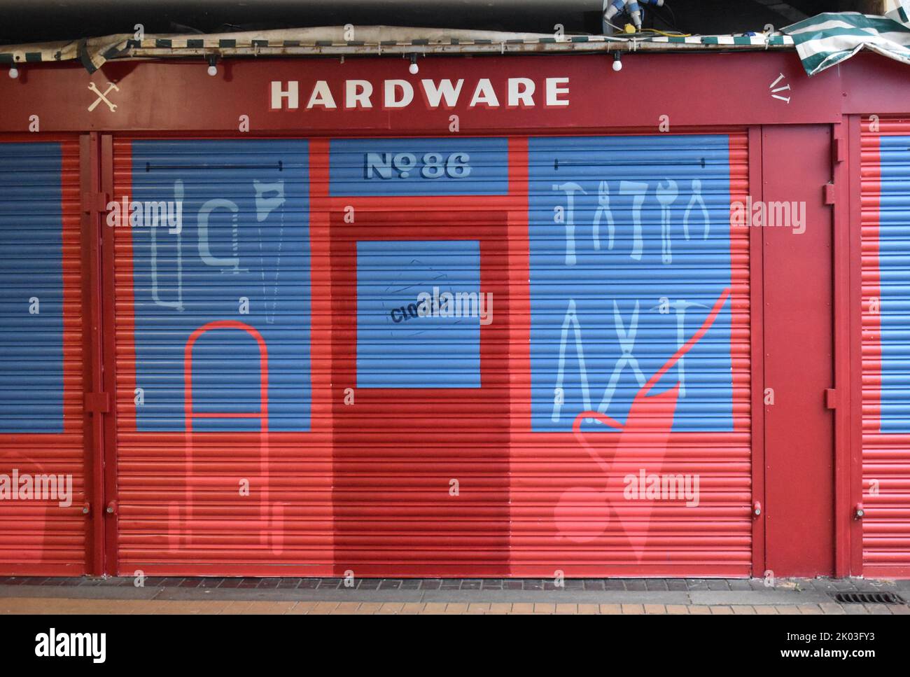 Colourful painted shutter on a stall in Milton Keynes open air market, indicating that it sells hardware. Stock Photo