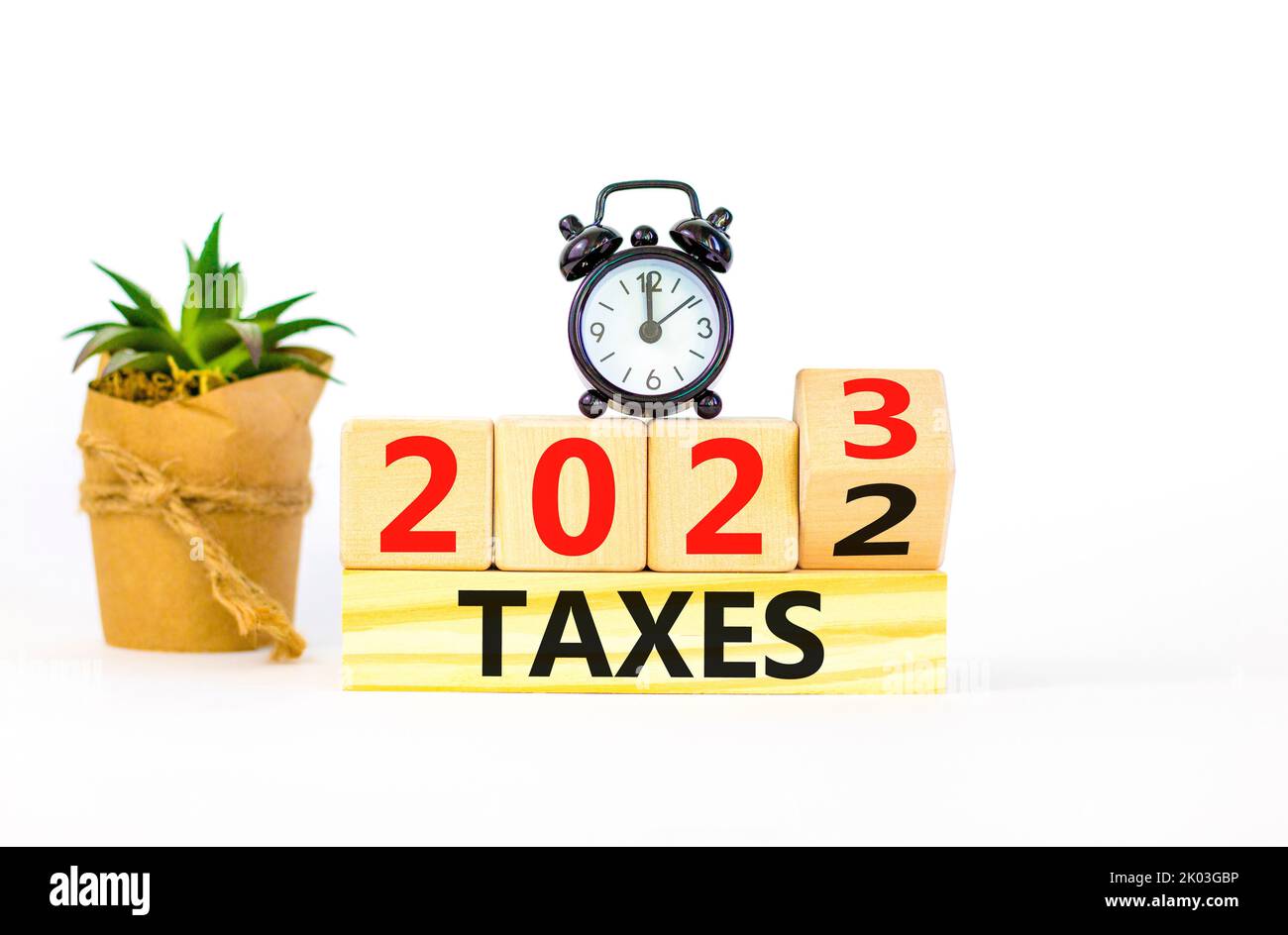 2023 Taxes New Year Symbol Turned Wooden Cube And Changes Words Taxes 2022 To Taxes 2023 Black Alarm Clock Beautiful White Table White Background 2K03GBP 