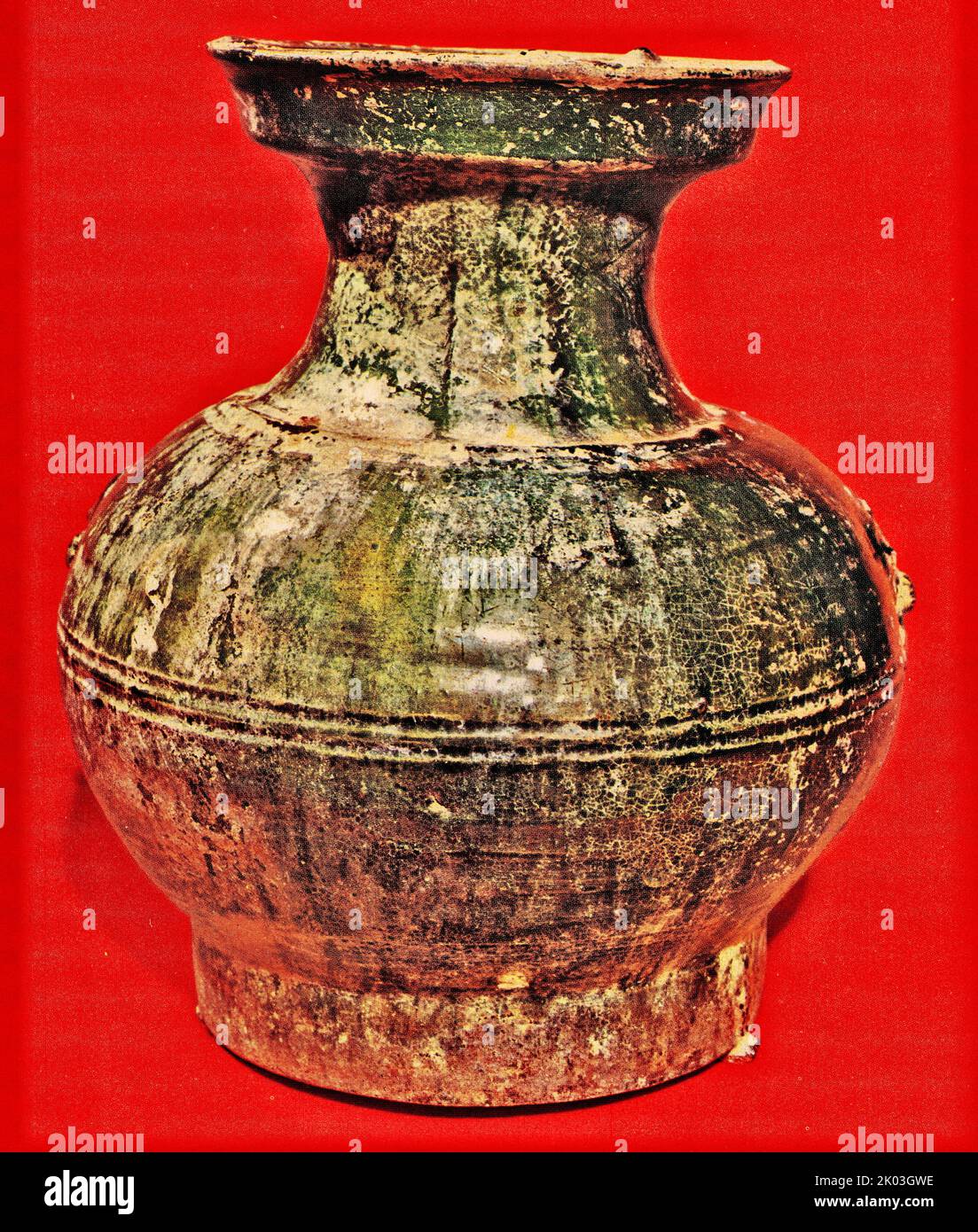 The round body has a slender neck and a flaring lip, and curves down to the round flat base. This jar is decorated with grooves and low relief beasts. Parts of the green glaze has faded, the rest invited a layer of iridescent colours due to chemical changes while it was underground. It was fired at high temperature. Stock Photo