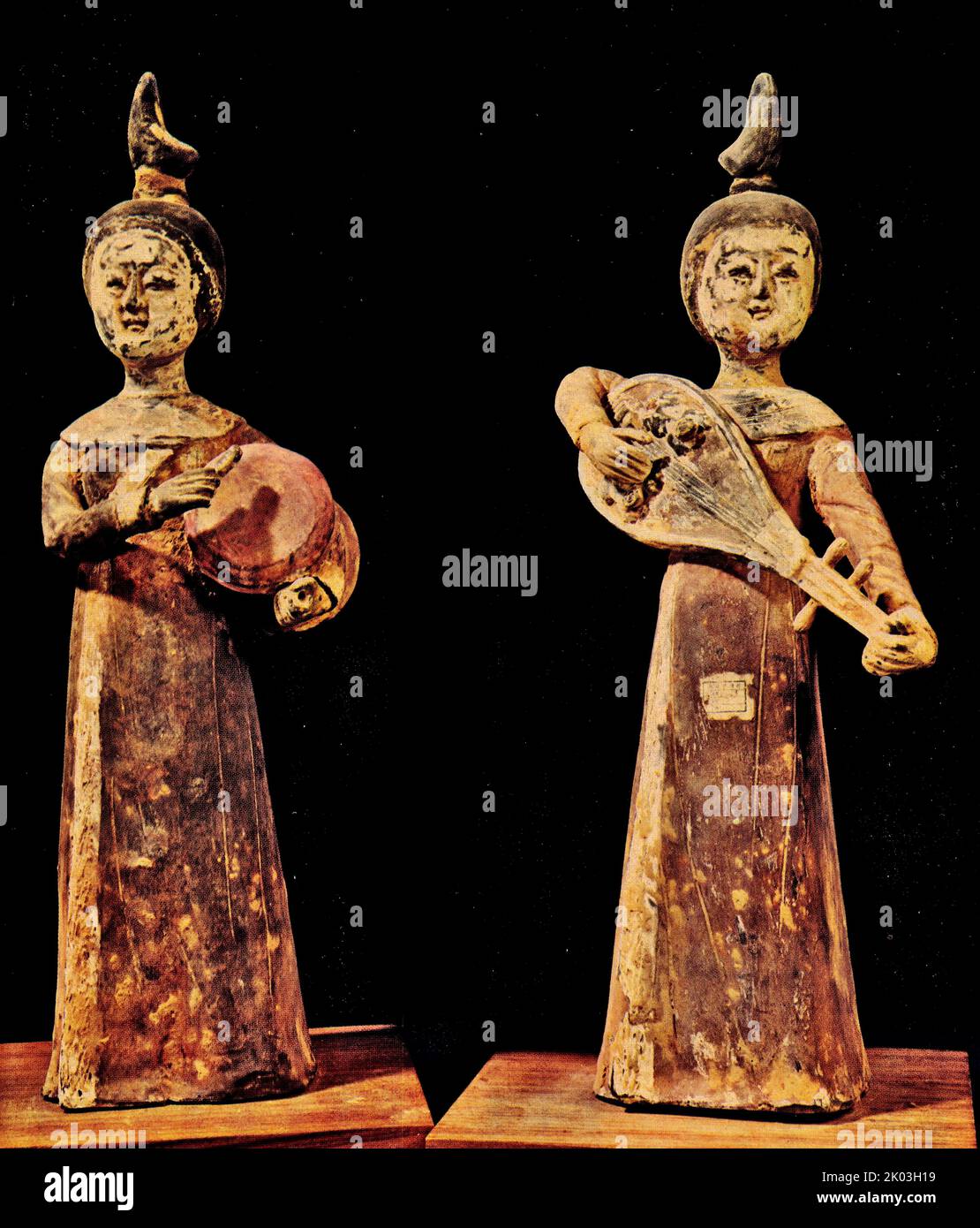 Six Dynasties figurines with the same clothing and hair accessories, with hair tied to the head, round faces, and delicate eyebrows. They are wearing long robes with round necks, shawls on their shoulders, sleeves, their shirts reaching the ground, and their shoes are not exposed. The soil is dark, the body is painted with red ink and white powder, there is a lot of white powder left on the face, and the hair is black. The right figurine holds the pipa, the left figurine holds the top of the pipa handle, the lower part of the pipa rests on the right armpit, and the right hand plays the stance, Stock Photo