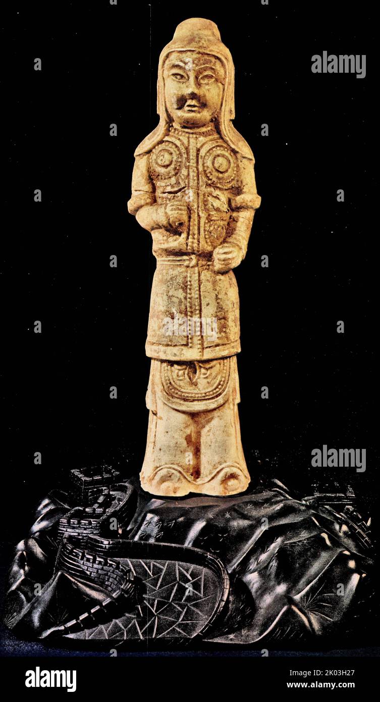 Sui Dynasty figurine wears a helmet, which also has a cloth underneath to provide an extra cover. This officer's armor covers the knees. There is a hole in one of the clenched hands for holding a lost weapon. Although originally painted in red and black and glazed all over in light yellow, most of the pigments have been replaced by incrustations of earth. Stock Photo