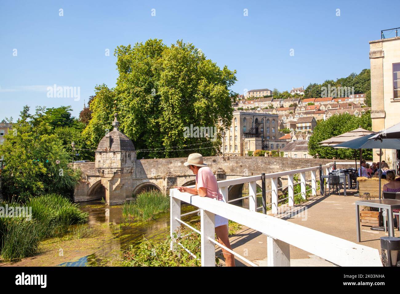 Woman viewing the river Avon passing under the old town bridge in the Wiltshire market town of Bradford on Avon  Wiltshire England Stock Photo