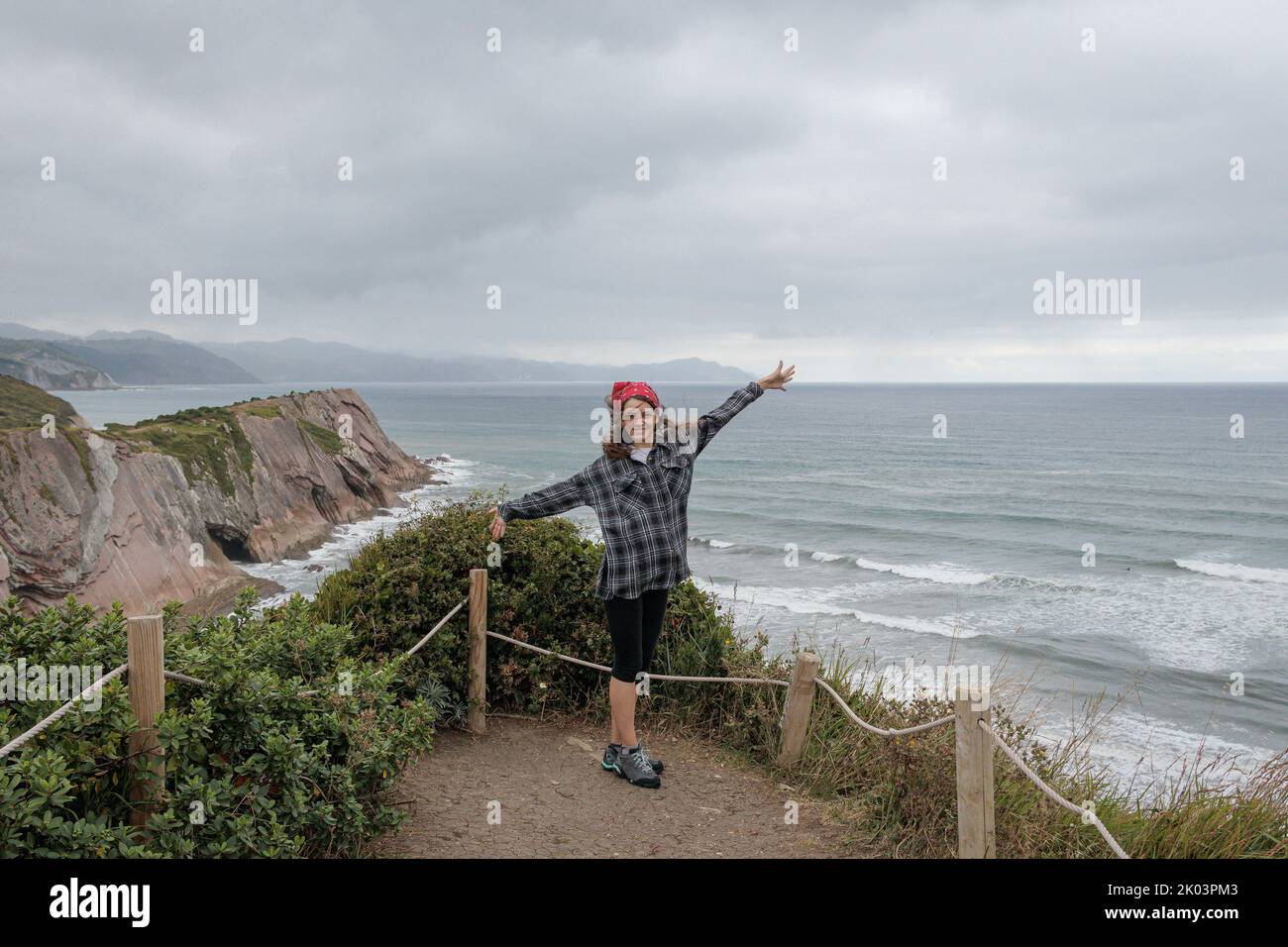 Happy tourist girl over Atlantic Ocean in Itzurun Beach in Zumaia, Basque Country, Spain. Stock Photo
