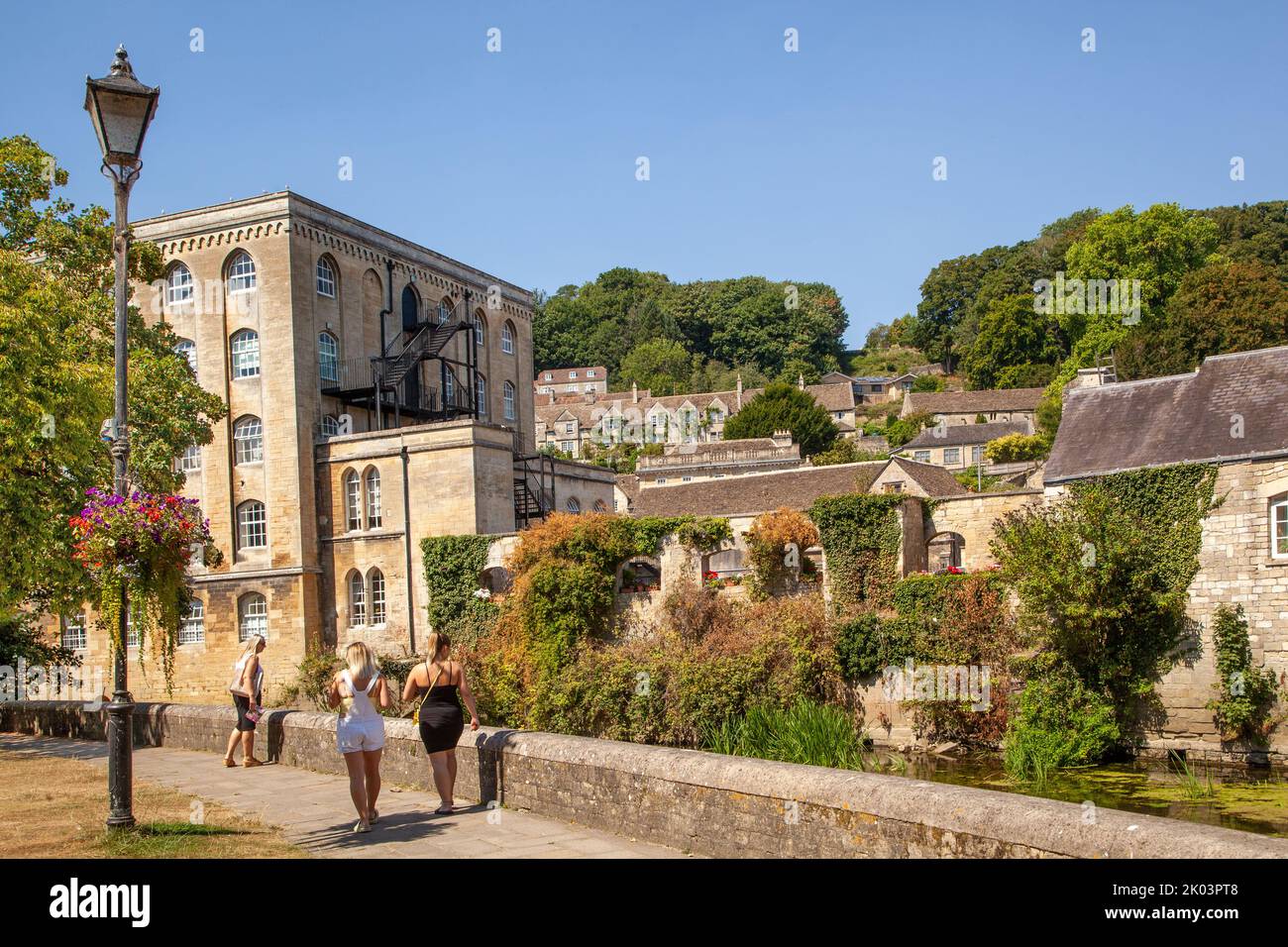 People on the walk along the banks of the river Avon in Bradford on Avon Wiltshire with a view of the old Abbey mill Stock Photo