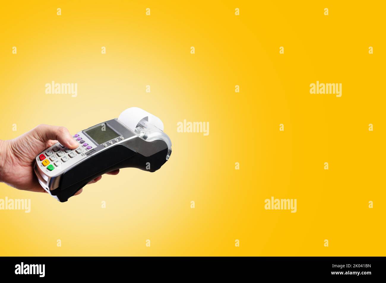On a bright yellow background, a cash terminal in a person's hand ...