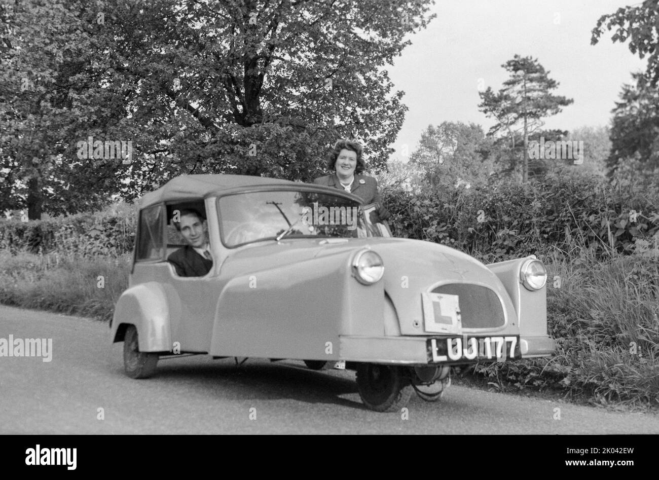 Vintage black and white photograph taken in the 1950s showing couple with their 3 wheeler Bond Minicar Mark C, registration LUJ 177. Taken in England. Stock Photo