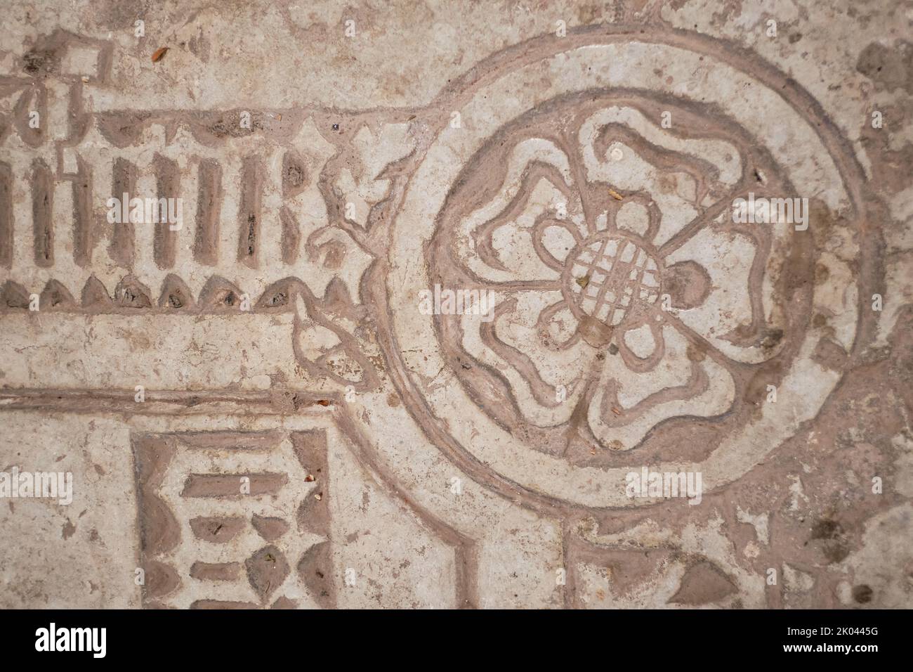 Carved symbol of a five-petaled rose with a globe on a stone tomb slab or epitaph. Stock Photo