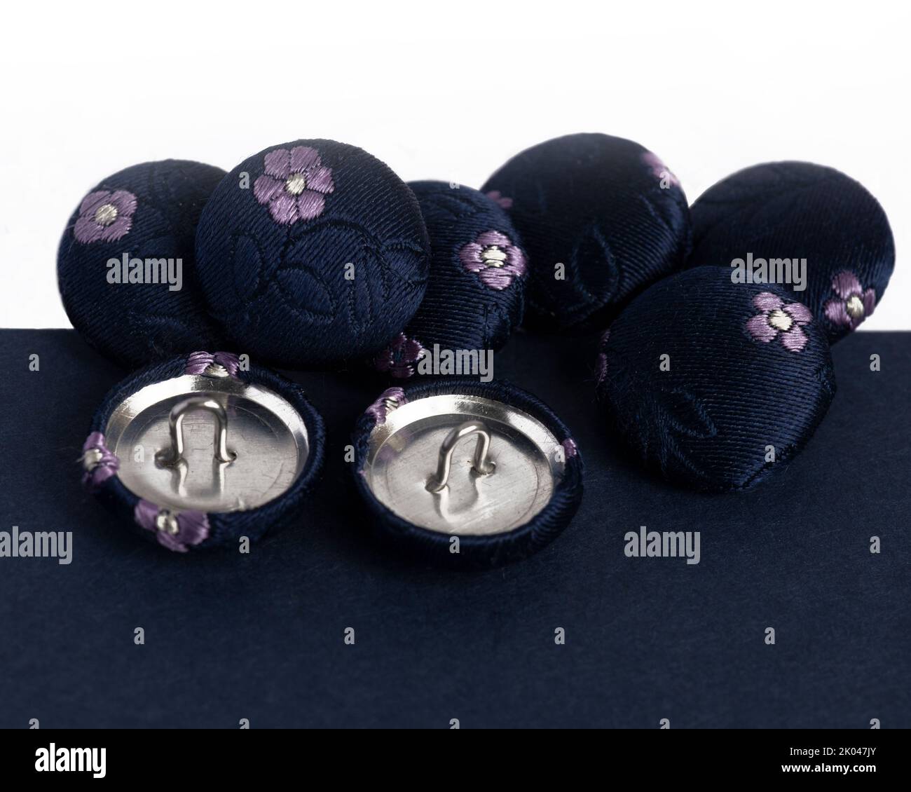 row of navy silk covered fabric buttons for handmade crafts in haberdashery sewing concept of hobbies on a white background Stock Photo