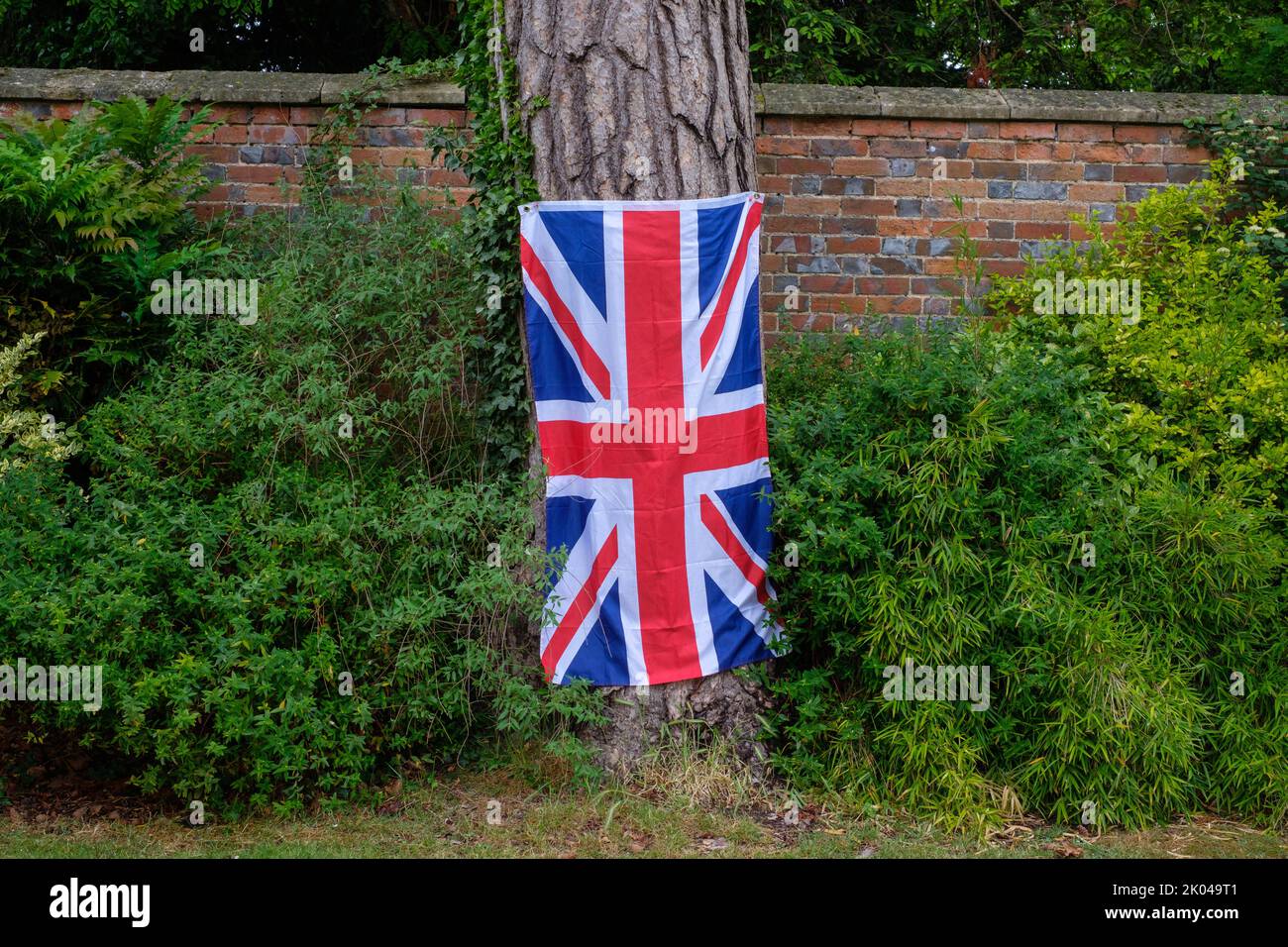 A Union Flag hangs on a tree trunk at a Platinum Jubilee party for  Her Majesty Queen Elizabeth II Stock Photo