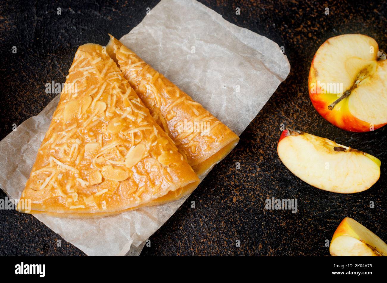 Delicious apple fruit leather sheets on a board and fruits on dark