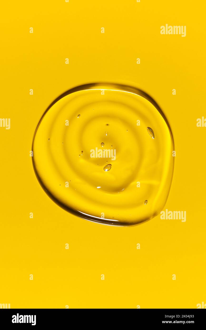 Clear transparent round spiral liquid gel drop or smear isolated on yellow background. Top view. Virus protection or cosmetics concept. Serum texture Stock Photo