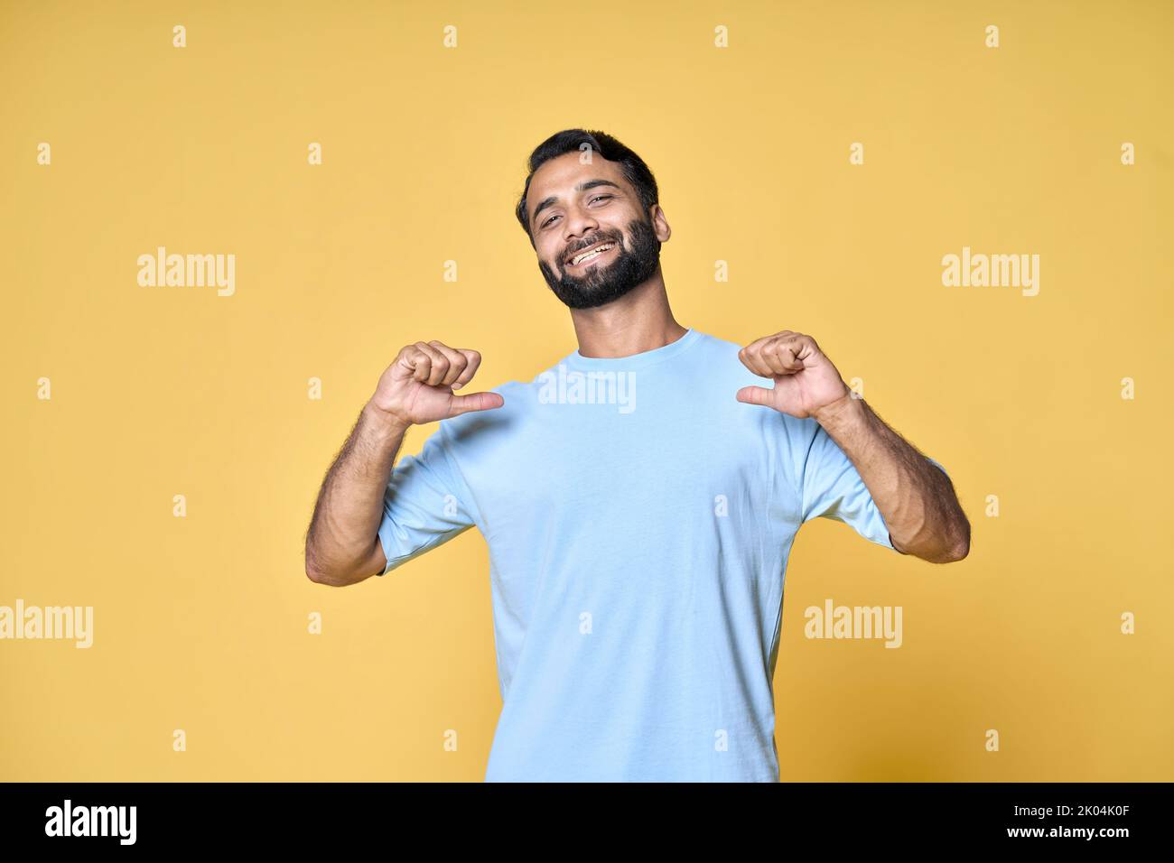 Smiling indian man standing isolated on yellow background pointing at himself. Stock Photo