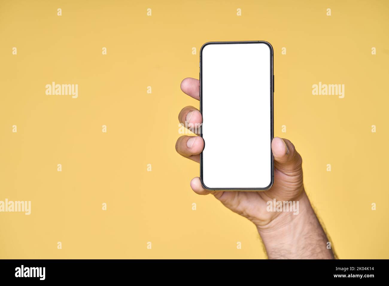 Male hand holding smartphone with white screen isolated on yellow background. Stock Photo