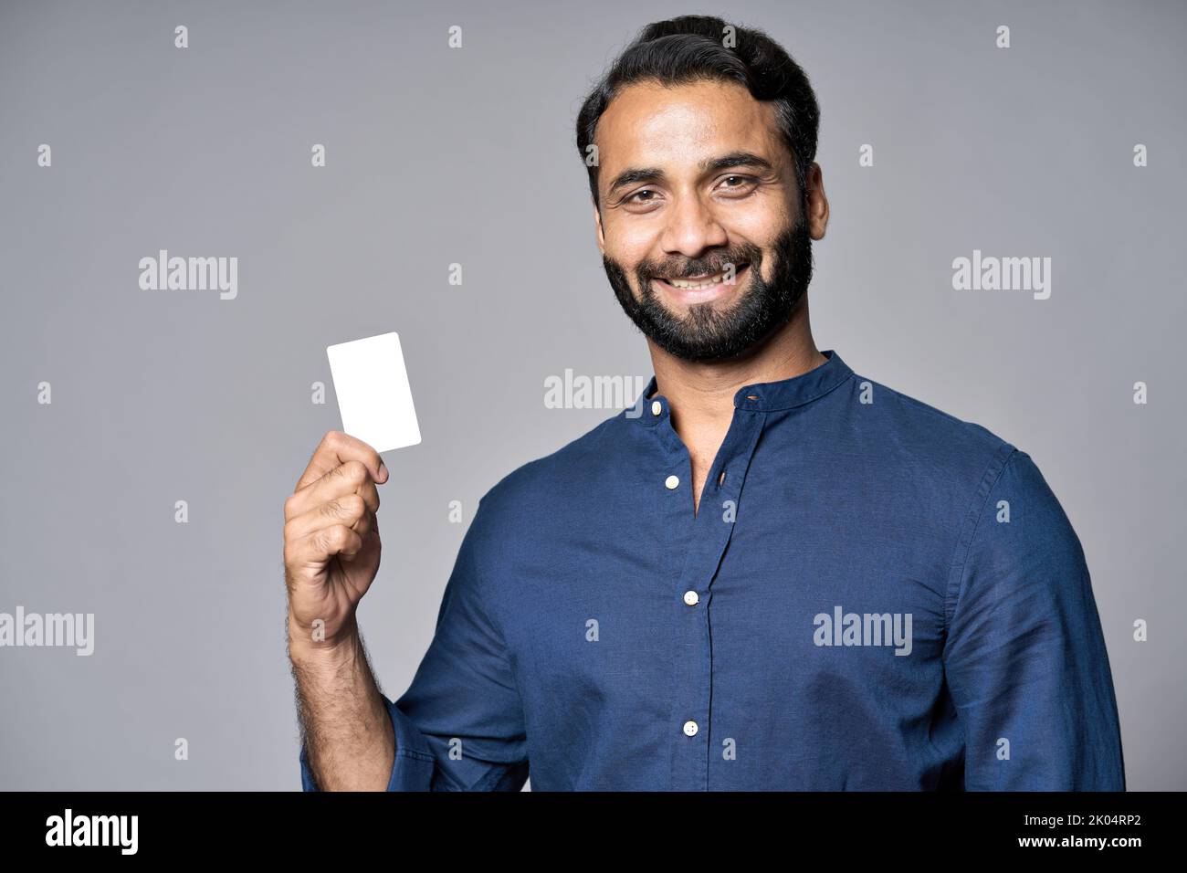 smiling indian business man holding credit card isolated on gray background 2K04RP2