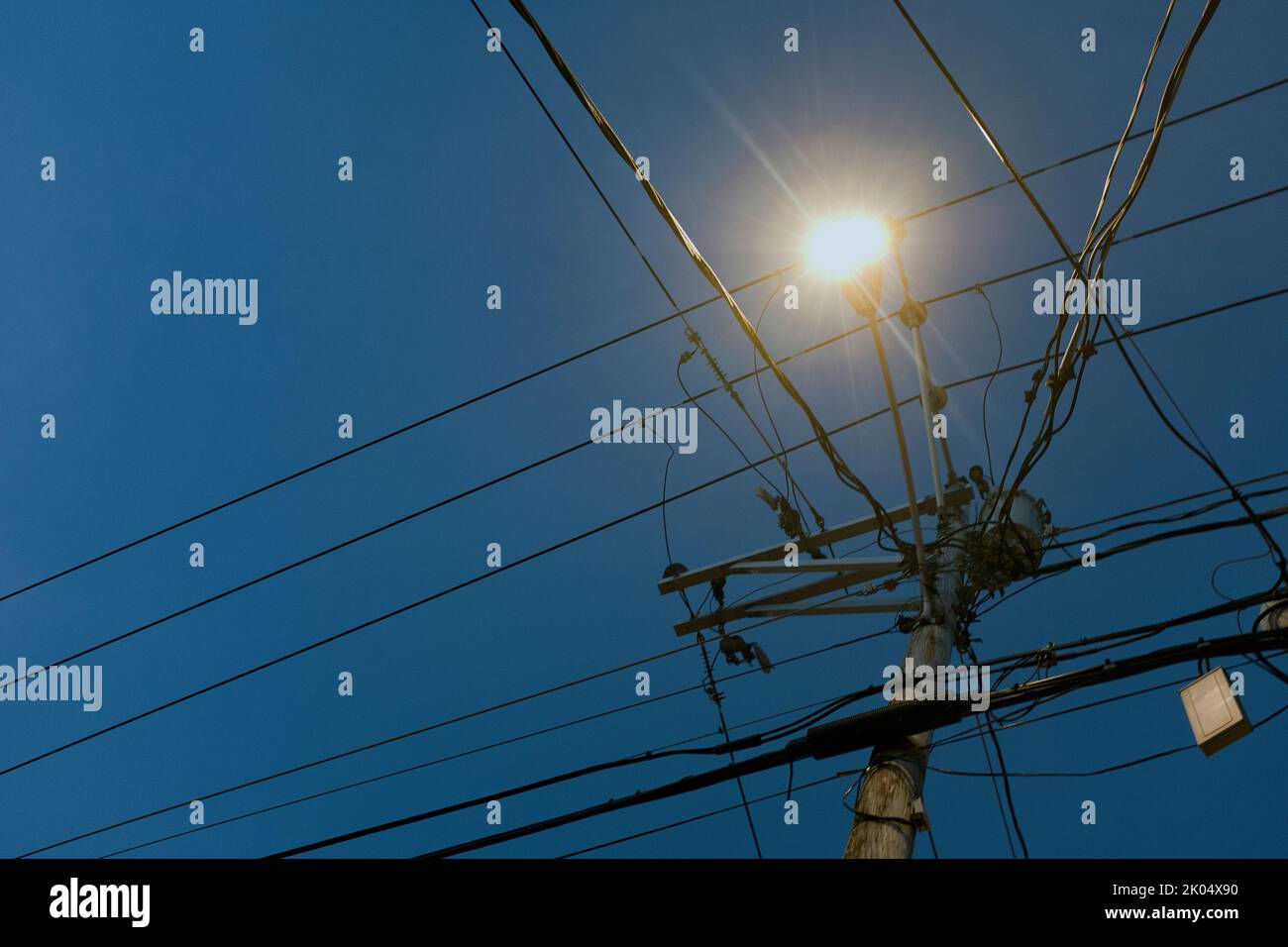 Low Angle View of illuminated Street Light and Utility Wires at Dusk Stock Photo