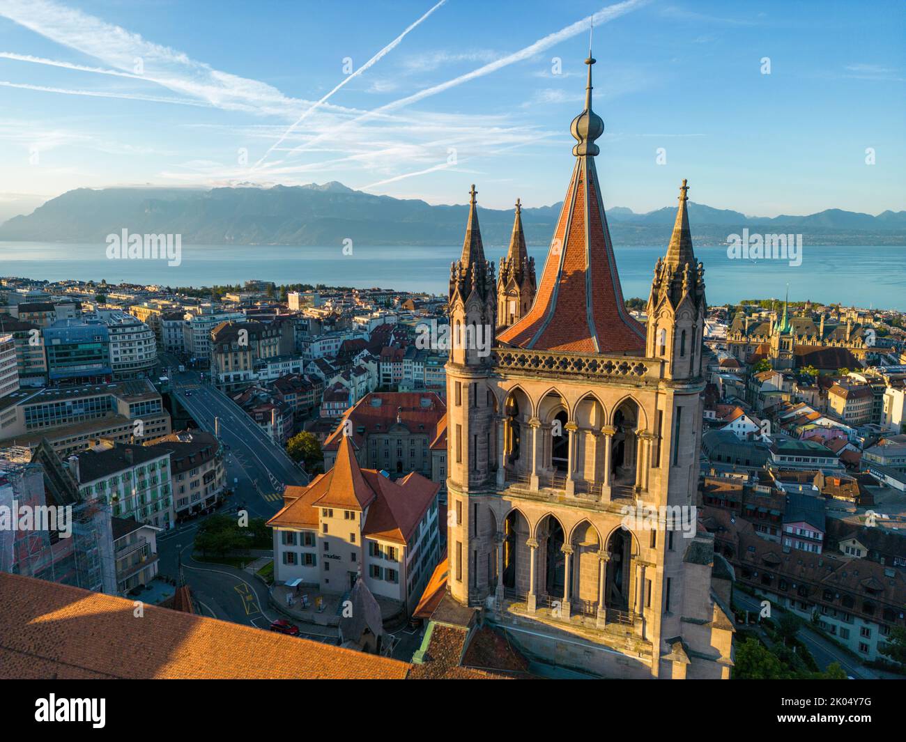 A drone aerial shot of Lausanne cathedral, the city, and Lake Geneva at sunrise in August Stock Photo