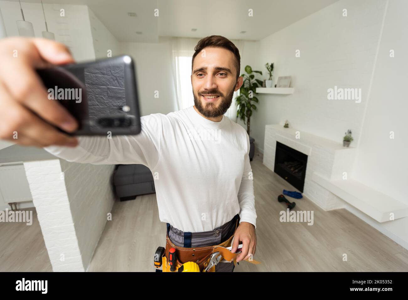 Smiling handsome young builder making selfie with mobile phone Stock Photo