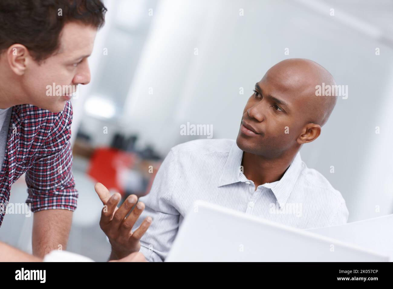 Discussing a few design issues. Two professionals having a work discussion while seated at a desk. Stock Photo