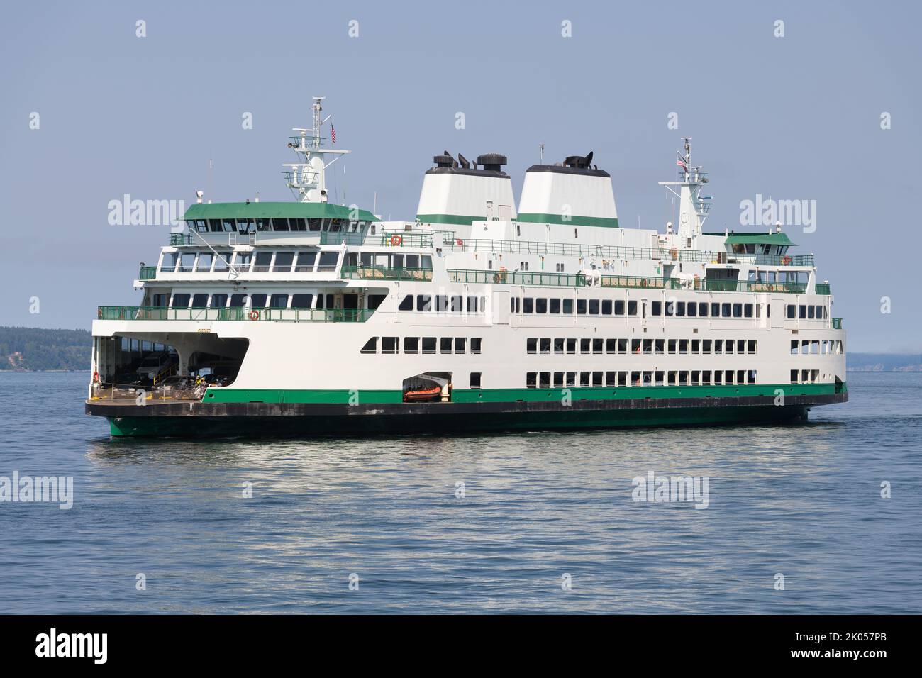 Green and white car ferry on calm water during day with blue sky Stock Photo