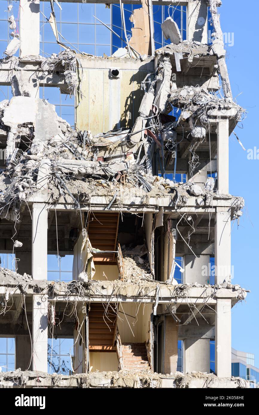 Rubble of partially demolished reinforced concrete bulding against modern glass building Stock Photo