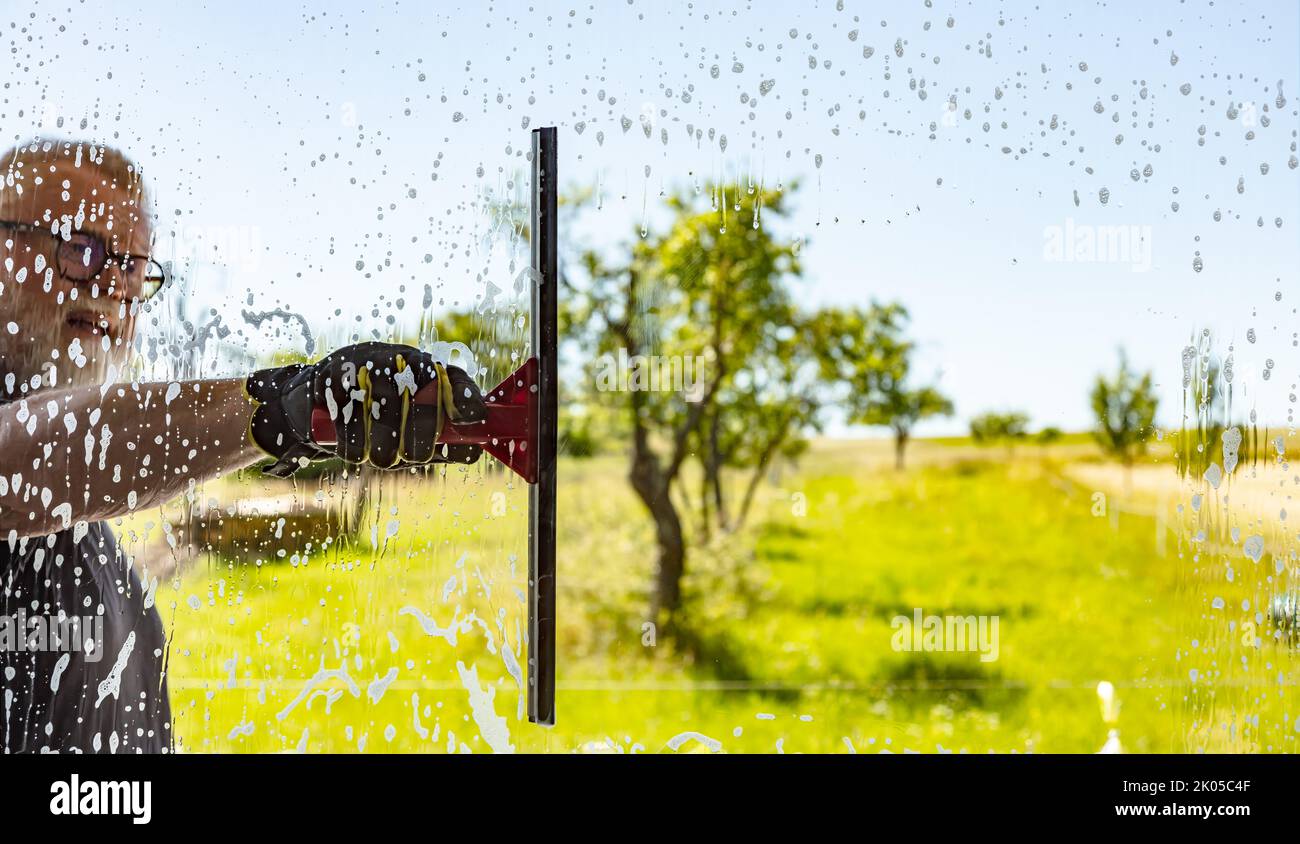 Man cleaning window with squeegee on a sunny Day Stock Photo