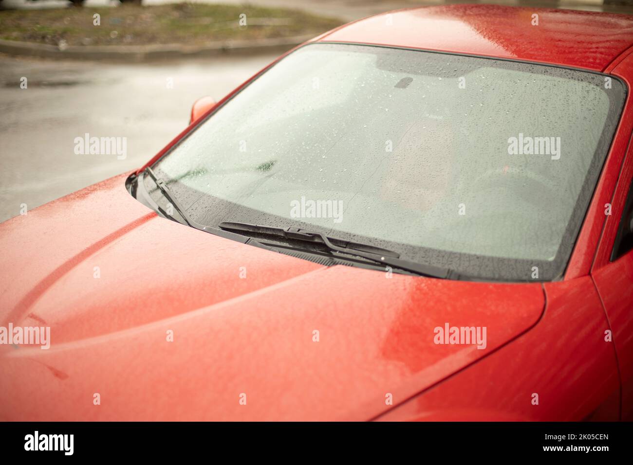 Red car. Wet car in parking lot. Windshield of transport. Stock Photo