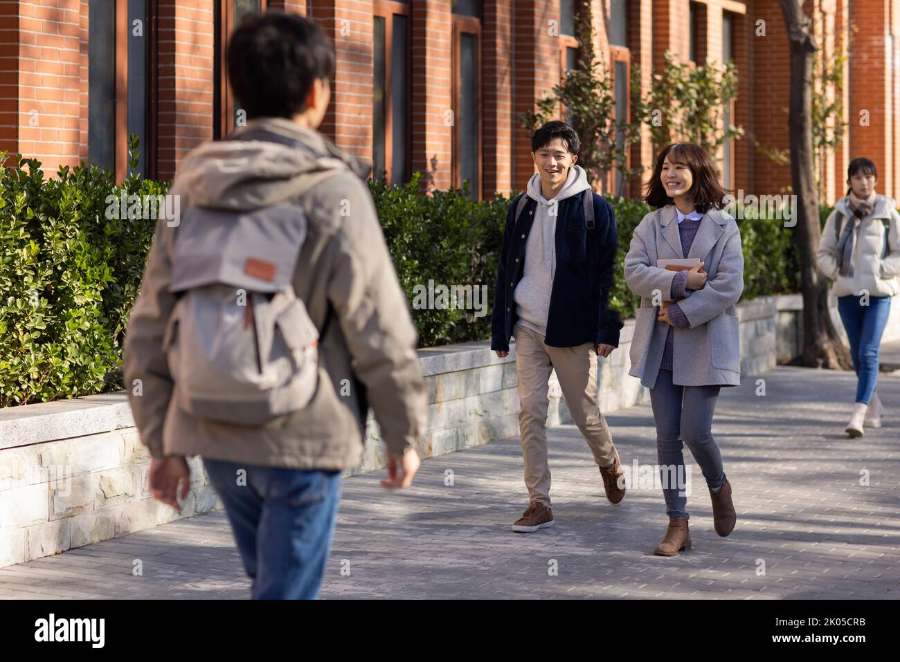 Happy Chinese college students walking on campus Stock Photo