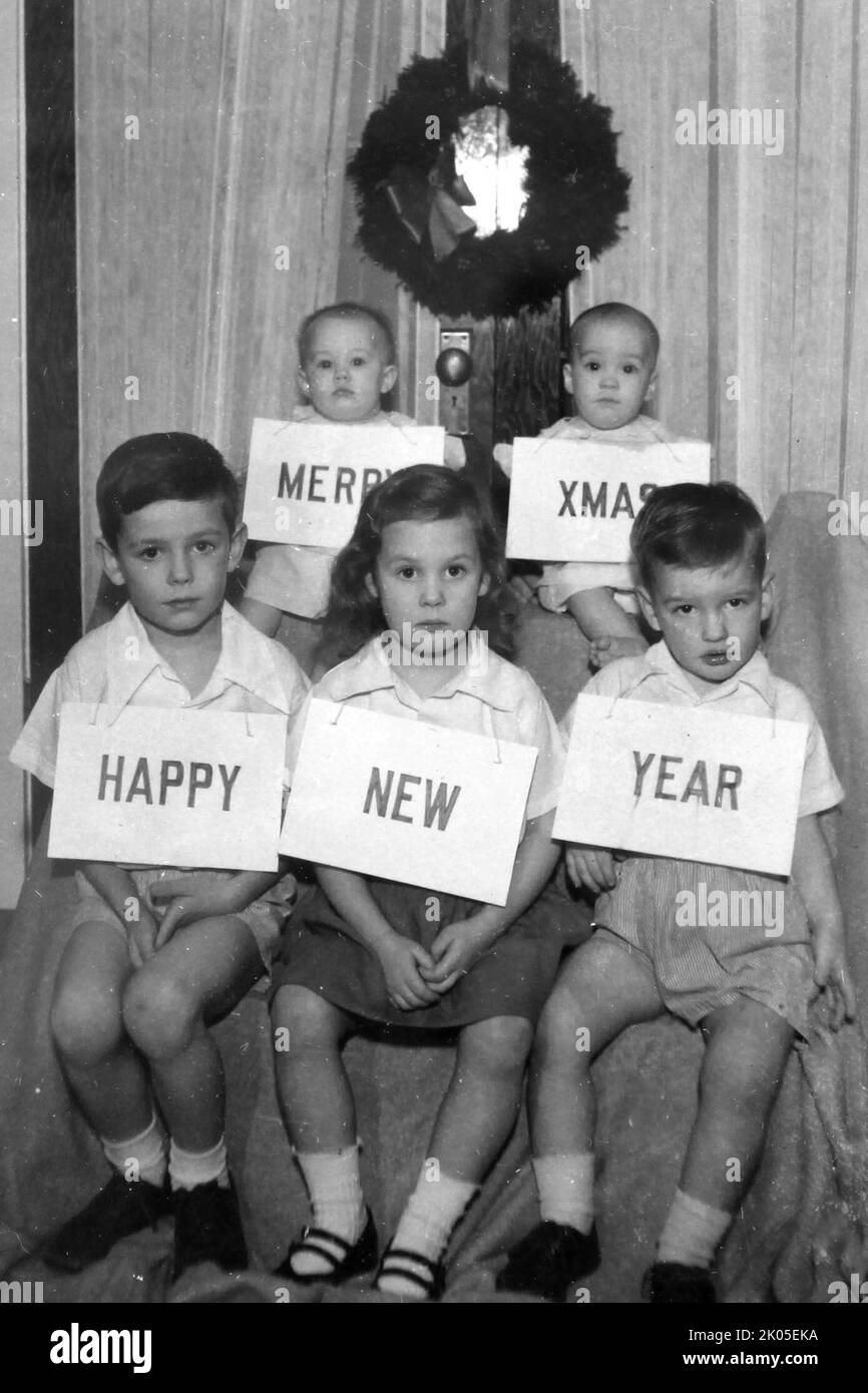 Five children look neither happy nor merry for a family Christmas card, ca. 1955. Stock Photo