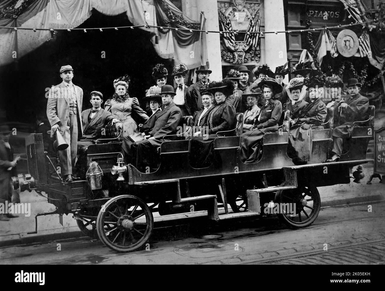An early bus carries a group of well dressed adults -- possibly in a patriotic parade, ca. 1895. Stock Photo