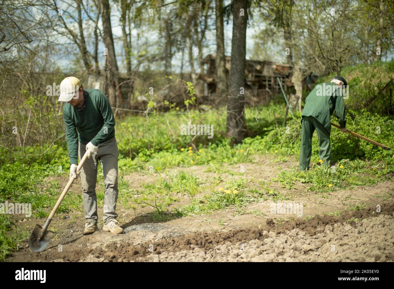 Guy digs soil with shovel. Digging up ground for planting. Work in garden. Life in countryside. Man works. Stock Photo